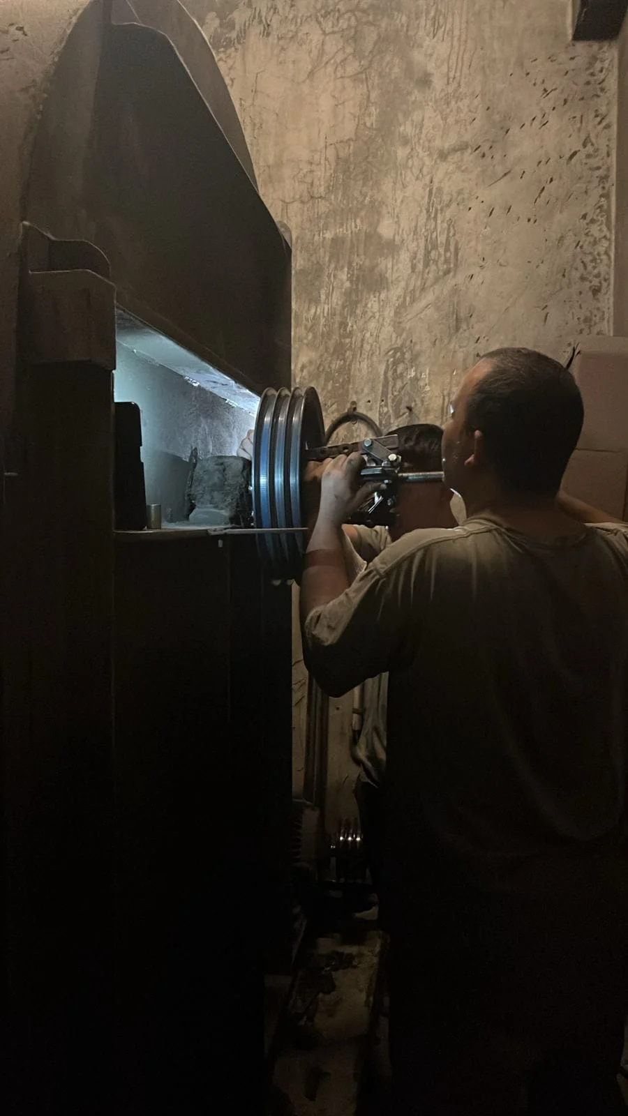 Técnico ajustando el conjunto de poleas de un equipo de ventilación
